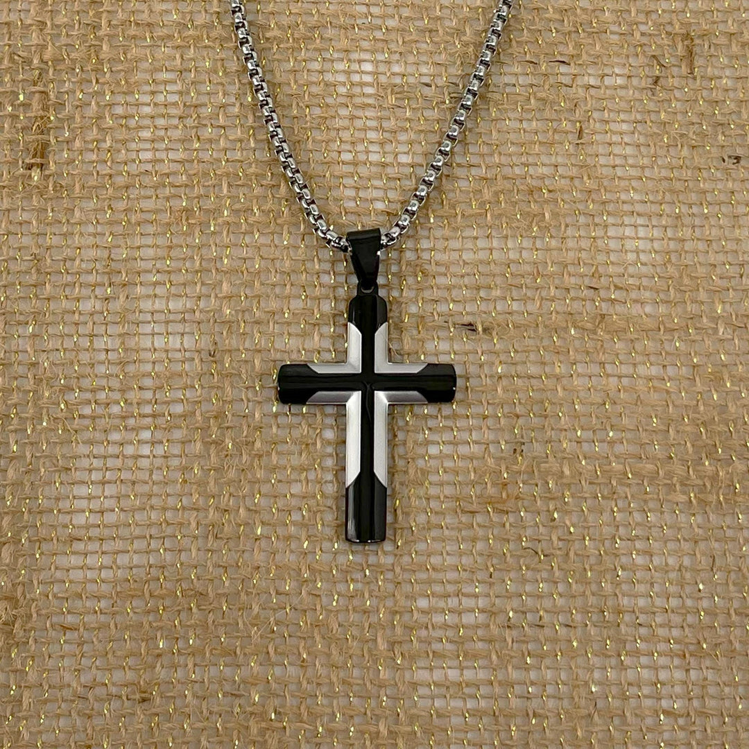 A silver-colored cross pendant necklace is displayed against a textured beige background.
