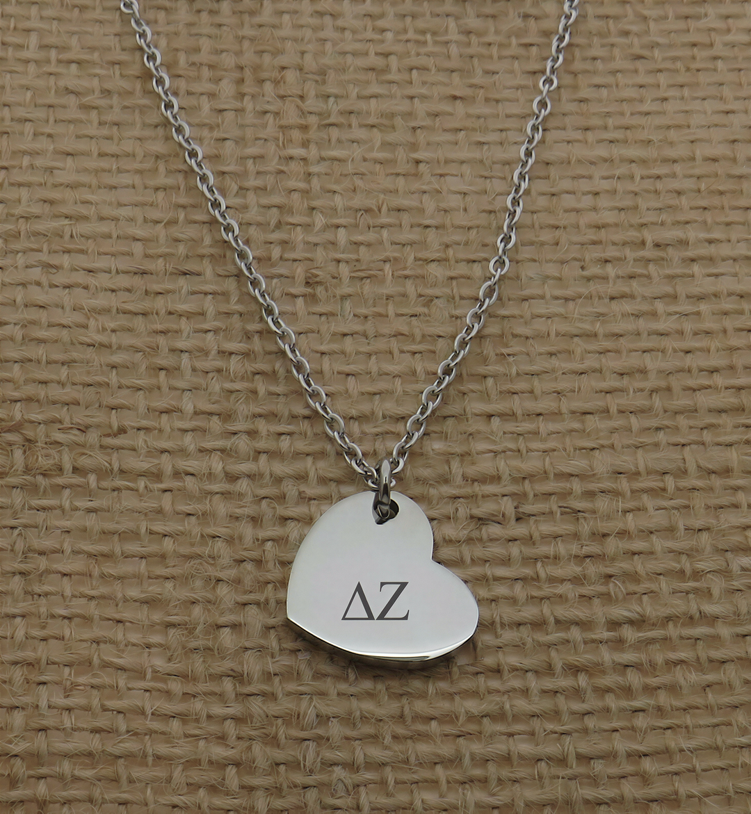 A silver heart-shaped charm necklace with the letters 'ΑΛ' engraved on it.