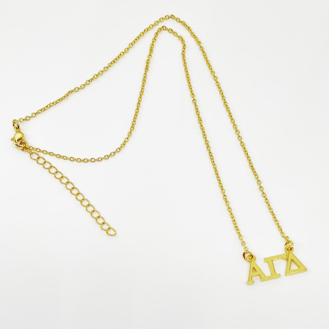A gold-colored necklace with a charm that says "ΑΛΑ" (Alpha Delta) on it.