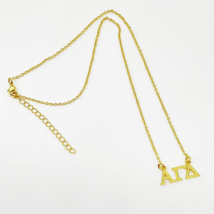 A gold-colored necklace with a charm that says "ΑΛΑ" (Alpha Delta) on it.
