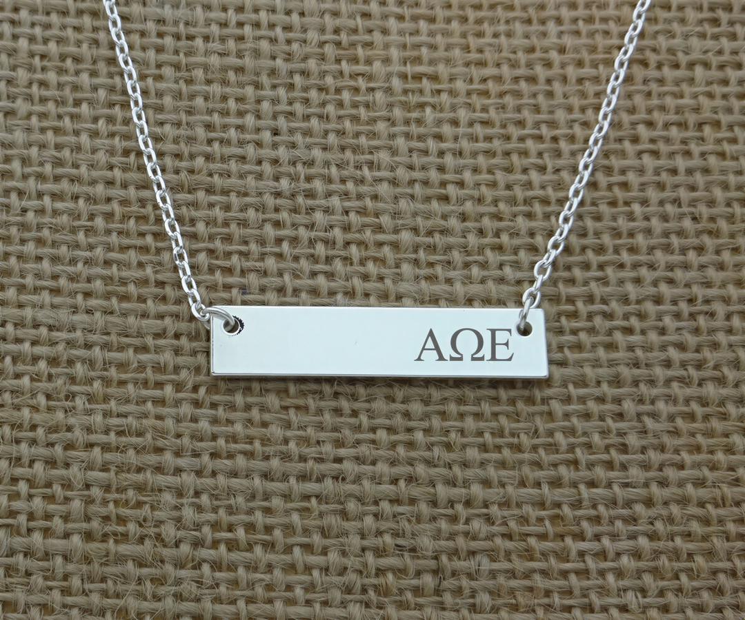 A silver necklace with a rectangular pendant engraved with the letters "AΔE".