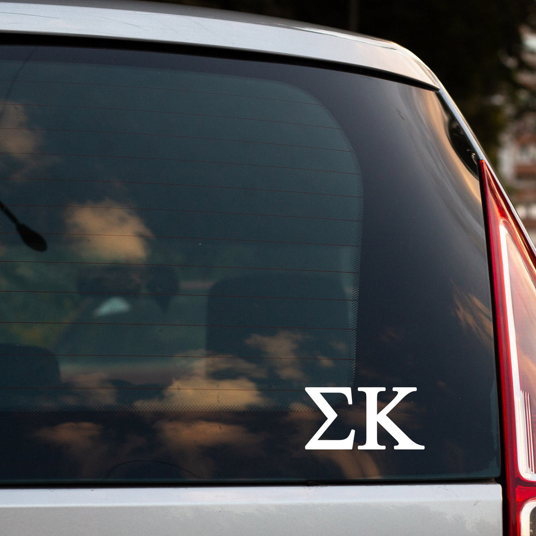 the rear window of a car with a white Greek letter logo, which appears to be a symbol or emblem associated with Greek sorority letters.