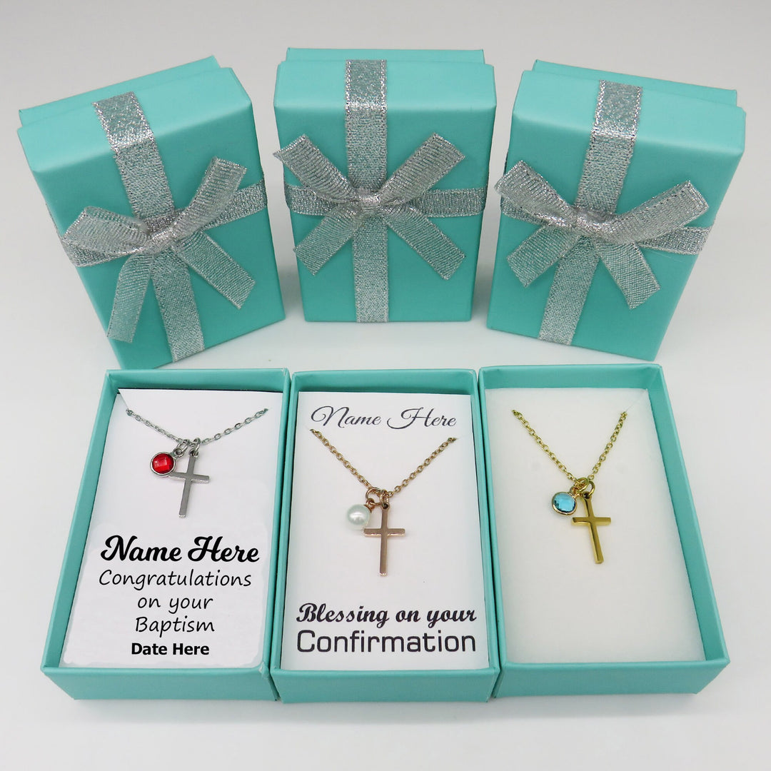 three turquoise gift boxes with silver ribbons, each containing a necklace with a cross pendant. The boxes are arranged in a row, and the necklaces are placed inside the boxes.