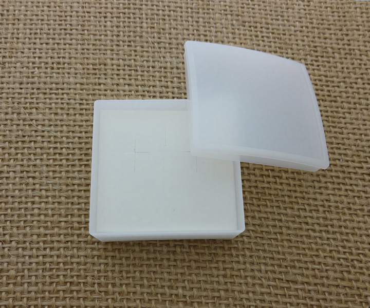 a white plastic box with a lid, placed on a woven surface.